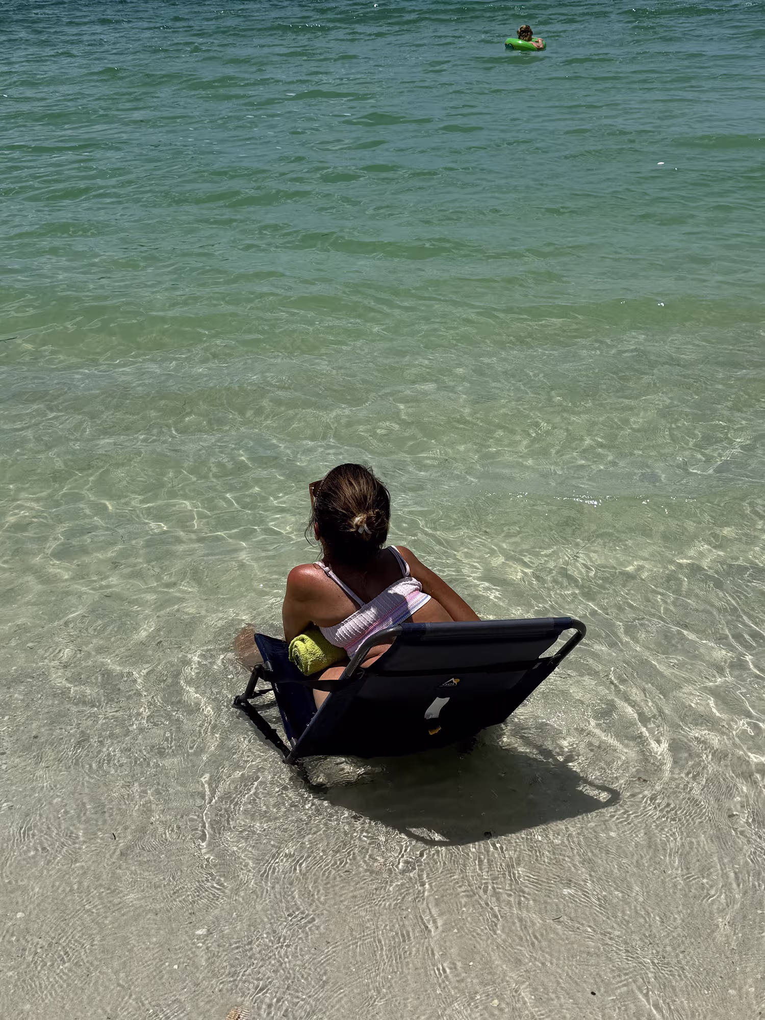 Traveler sitting in a low beach chair at the water’s edge in Clearwater Beach