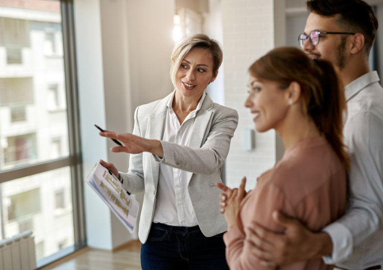 Real estate agent showing a property to a smiling couple inside an apartment.
