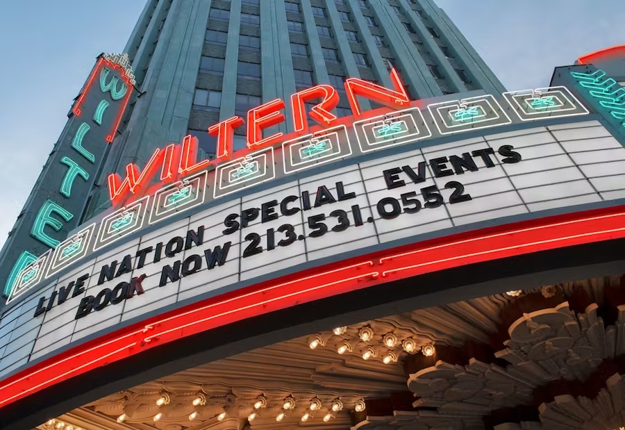 The Wiltern theater marquee at dusk with neon lights advertising Live Nation special events and booking phone number.