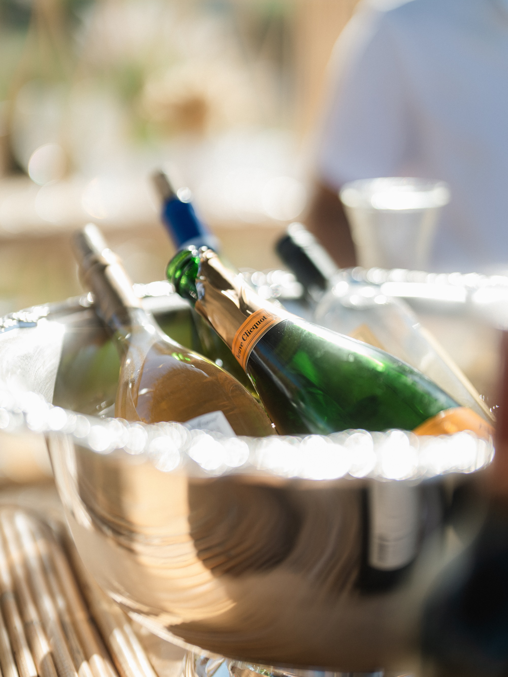 Silver ice bucket containing several bottles of wine and champagne including a Veuve Clicquot bottle.