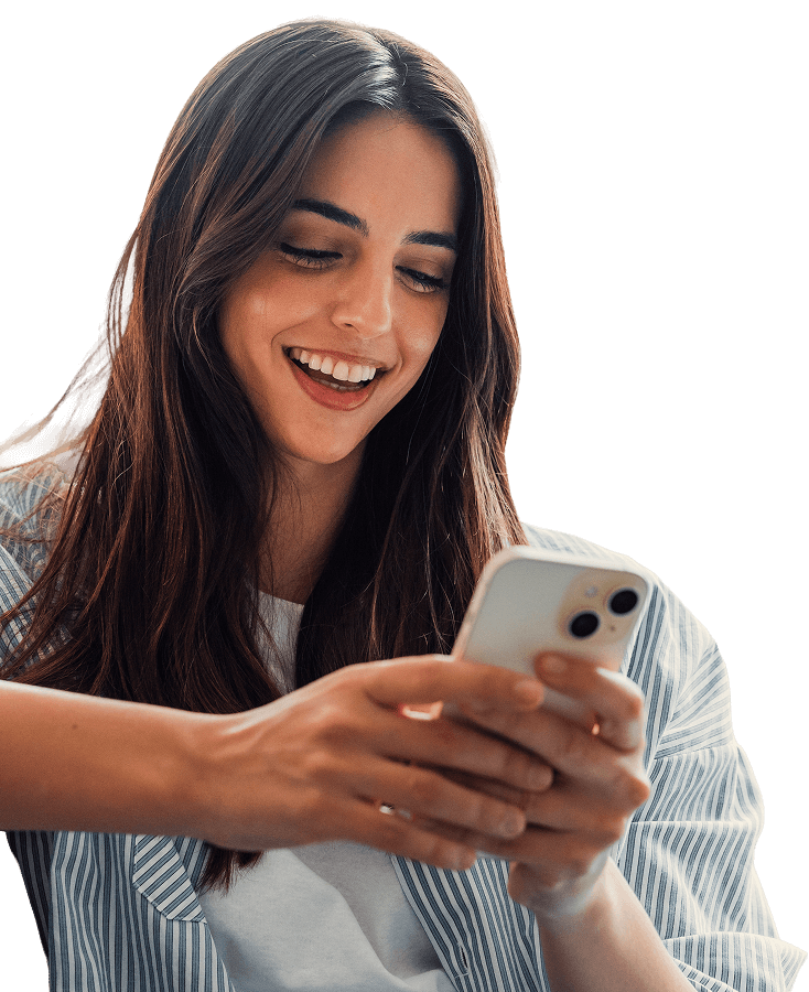 Mujer sonriente mirando un teléfono inteligente blanco mientras sostiene con ambas manos.