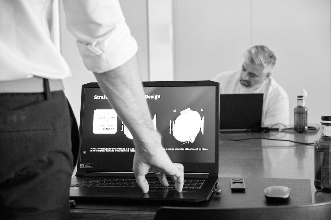 Instructure hand on laptio with student in background taking notes