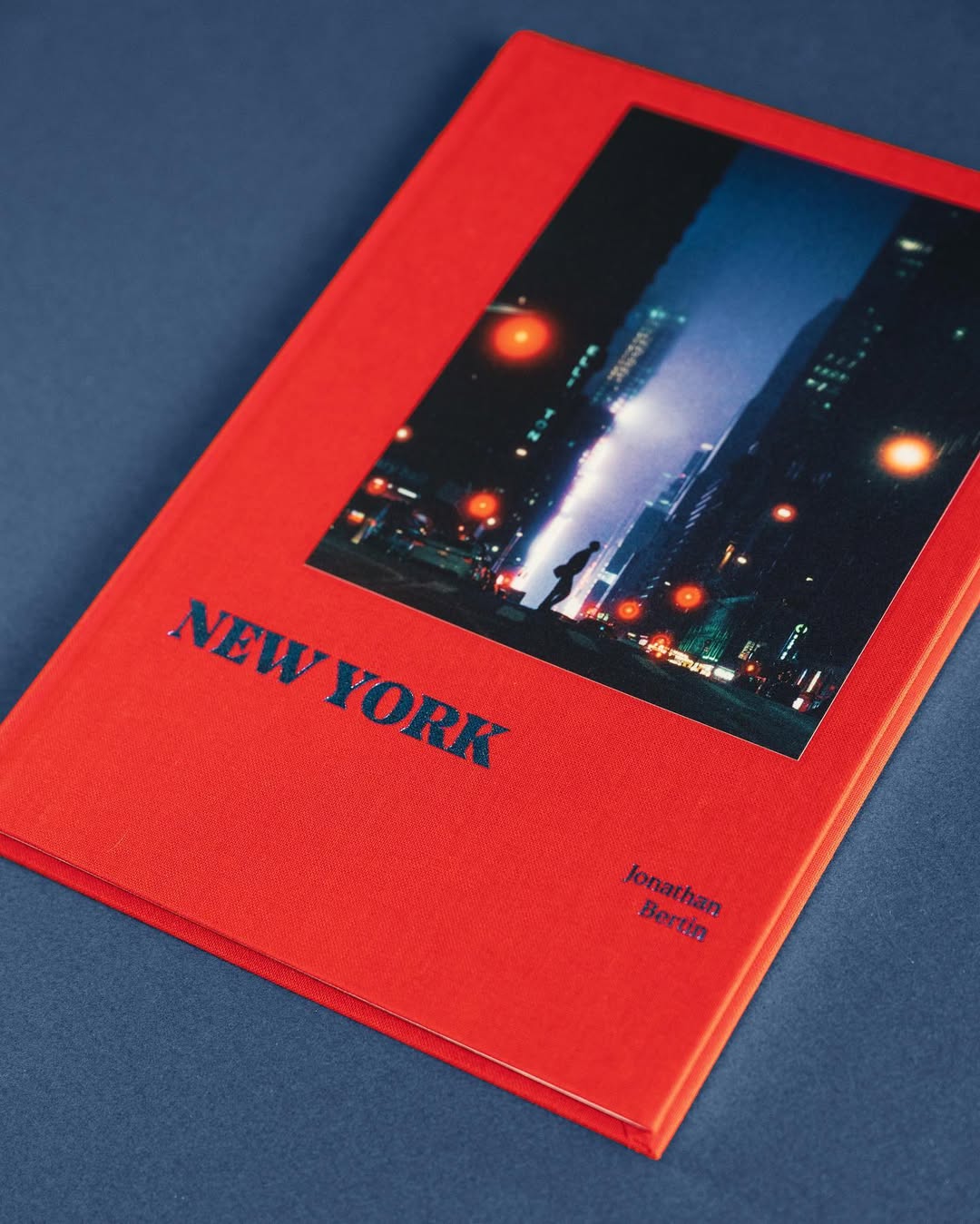 Red book titled 'NEW YORK' with a city nightscape photo of a silhouette on a street surrounded by lights on the cover.