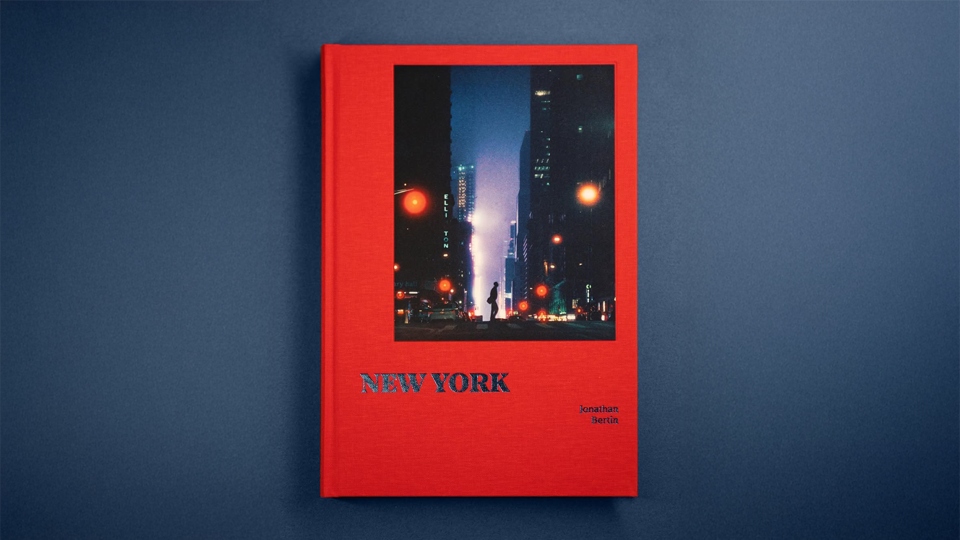 Red book cover featuring a nighttime cityscape photo of New York with streetlights and tall buildings, titled 'NEW YORK' by Jonathan Bertin.