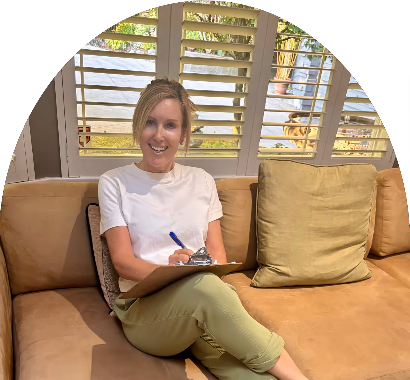 Lisa Otterstein sitting on a beige sofa, smiling with a clipboard in hand during a counseling session in North Vancouver.