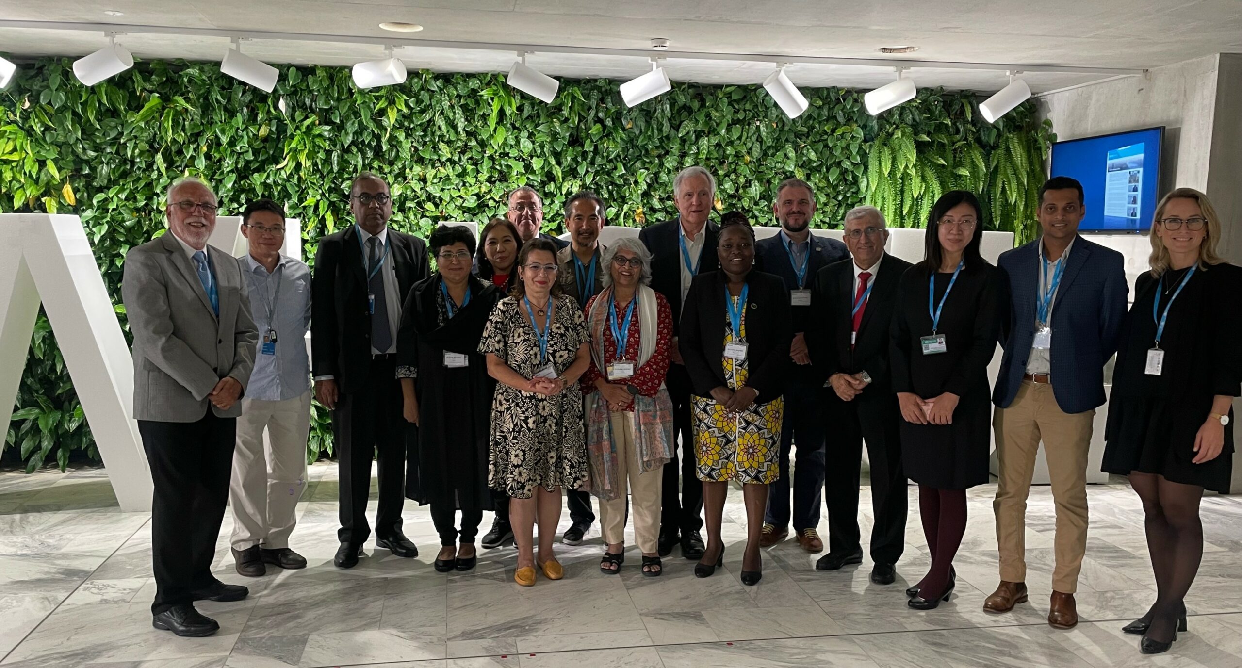 A group of people posing for a photo with a green plant wall in the background.