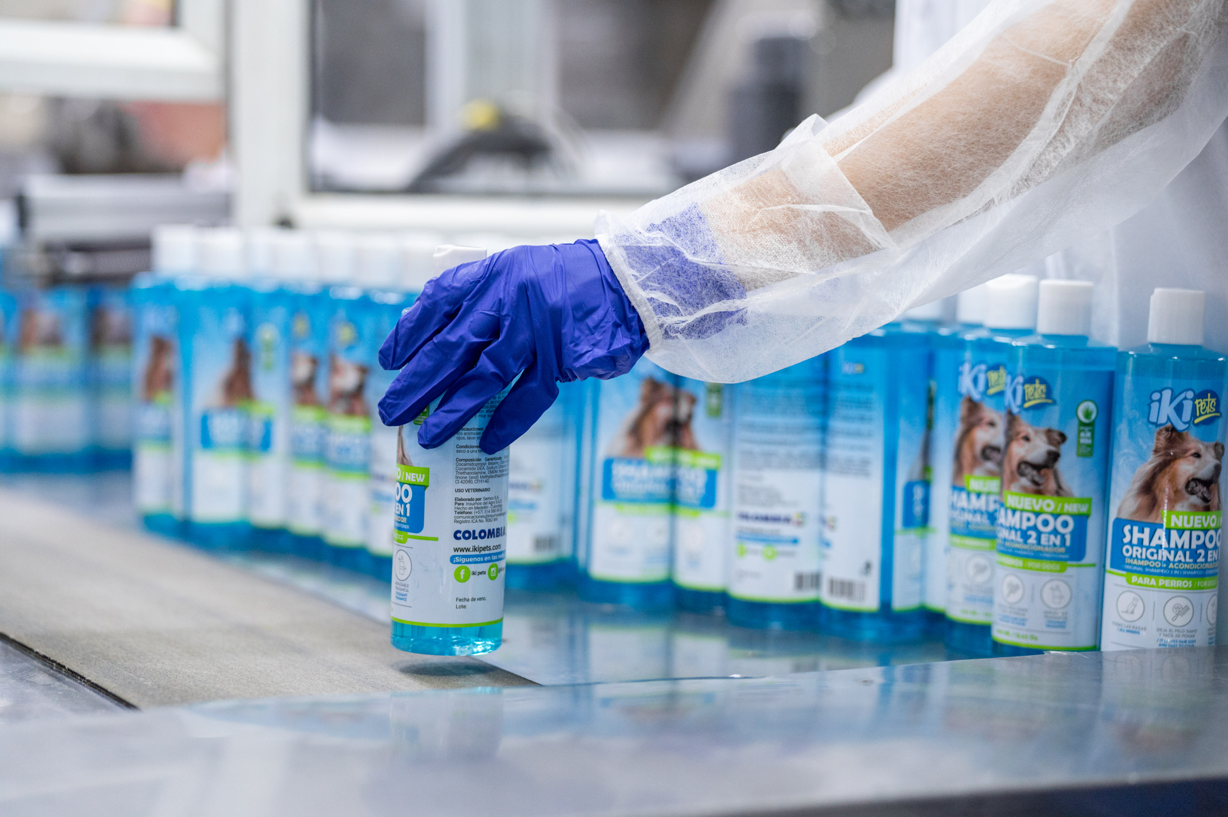 Cut-and-sew factory materials including fabric rolls, thread spools, and tailoring scissors on a worktable, representing textile manufacturing and fabric sourcing.