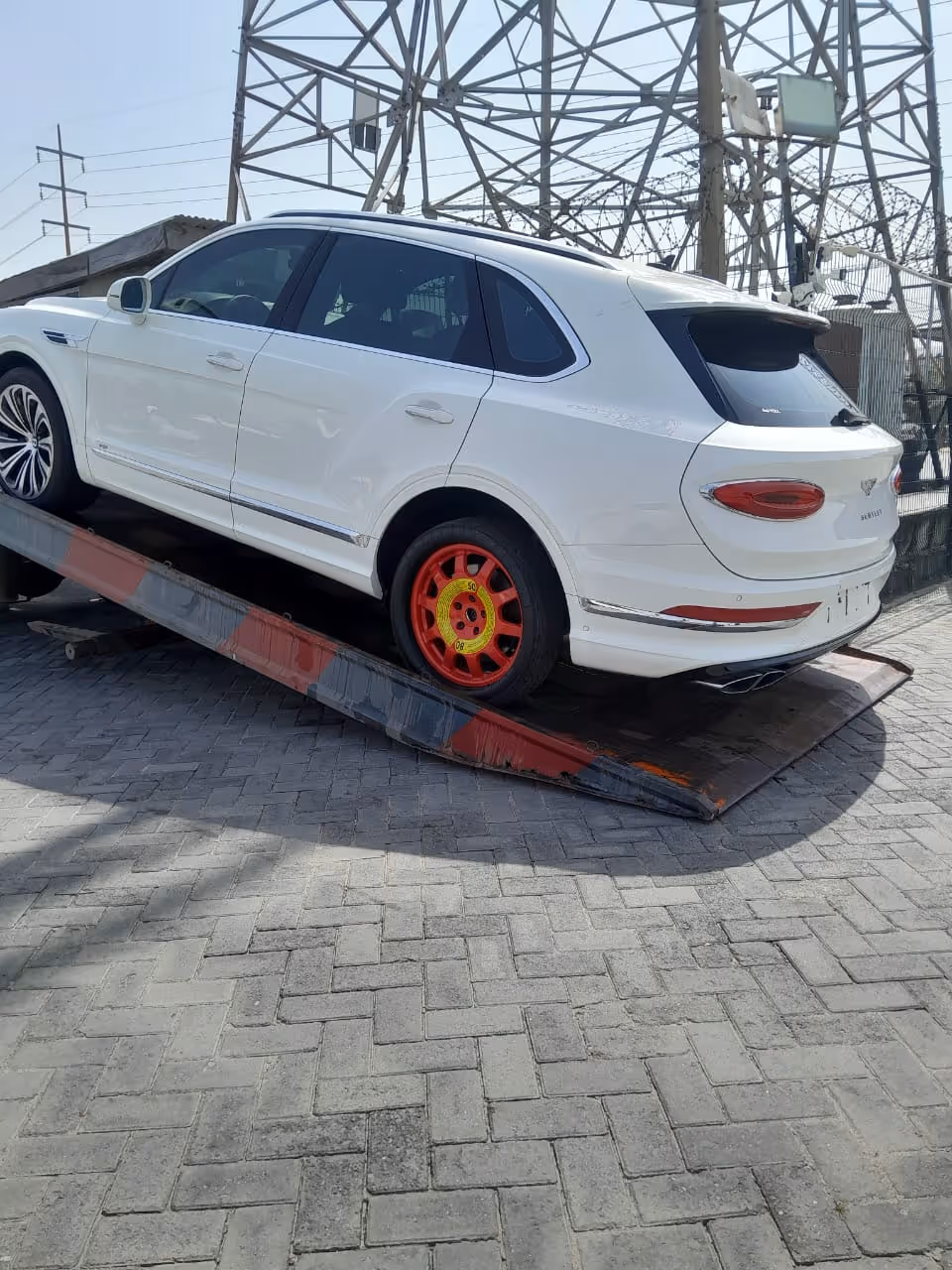 White luxury SUV on a ramp with a bright red spare tire on the rear wheel.
