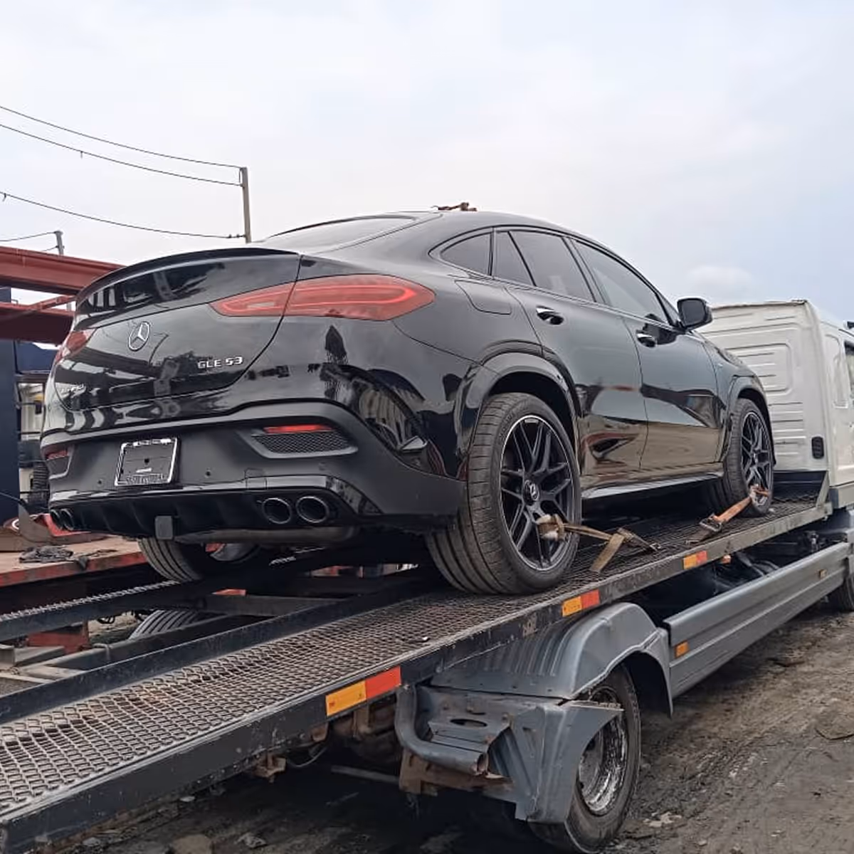 Black Mercedes-Benz GLE 53 SUV secured on a flatbed tow truck.