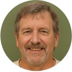 Smiling middle-aged man with short gray hair and a light beard against a green background.