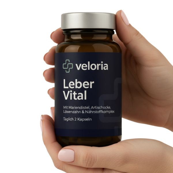 Hand holding a brown supplement bottle labeled 'veloria Leber Vital' with ingredients and dosage in German.