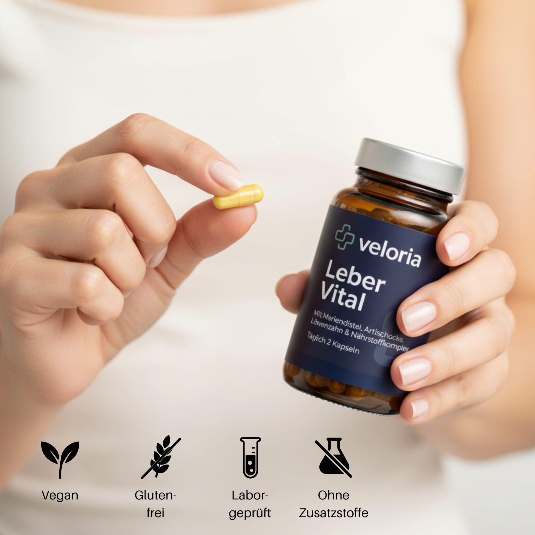 Hand holding a yellow capsule and a brown bottle labeled 'veloria Leber Vital' with icons below indicating vegan, gluten-free, lab-tested, and no additives.