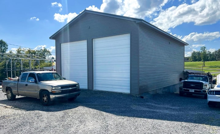 Gray metal building with two tall white garage doors.