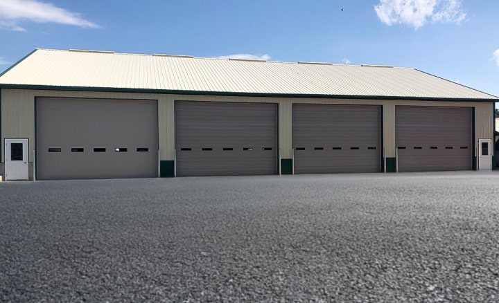 Long beige building with multiple garage bays and white doors.