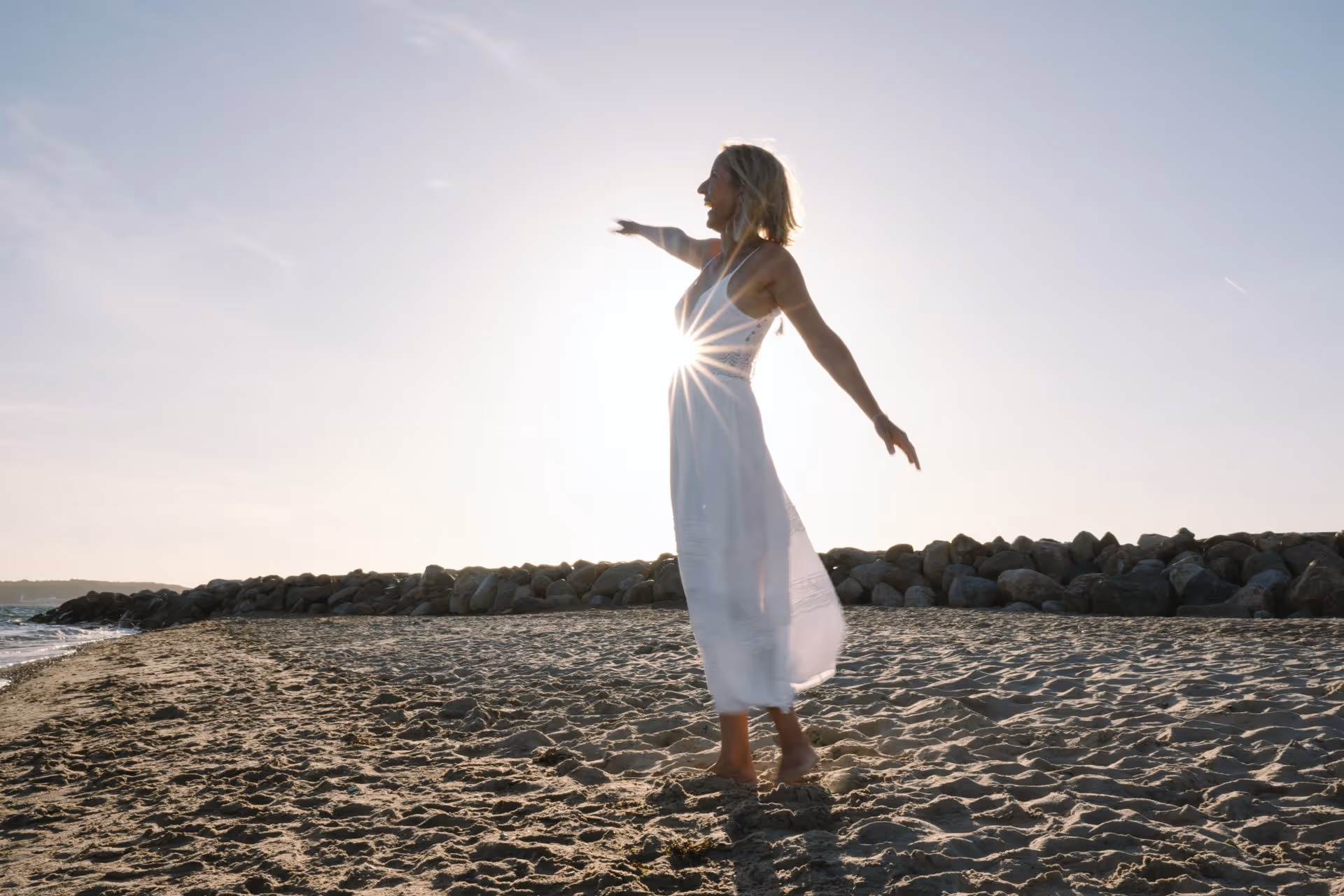Person mit Leichtigkeit im weißen Kleid am Strand