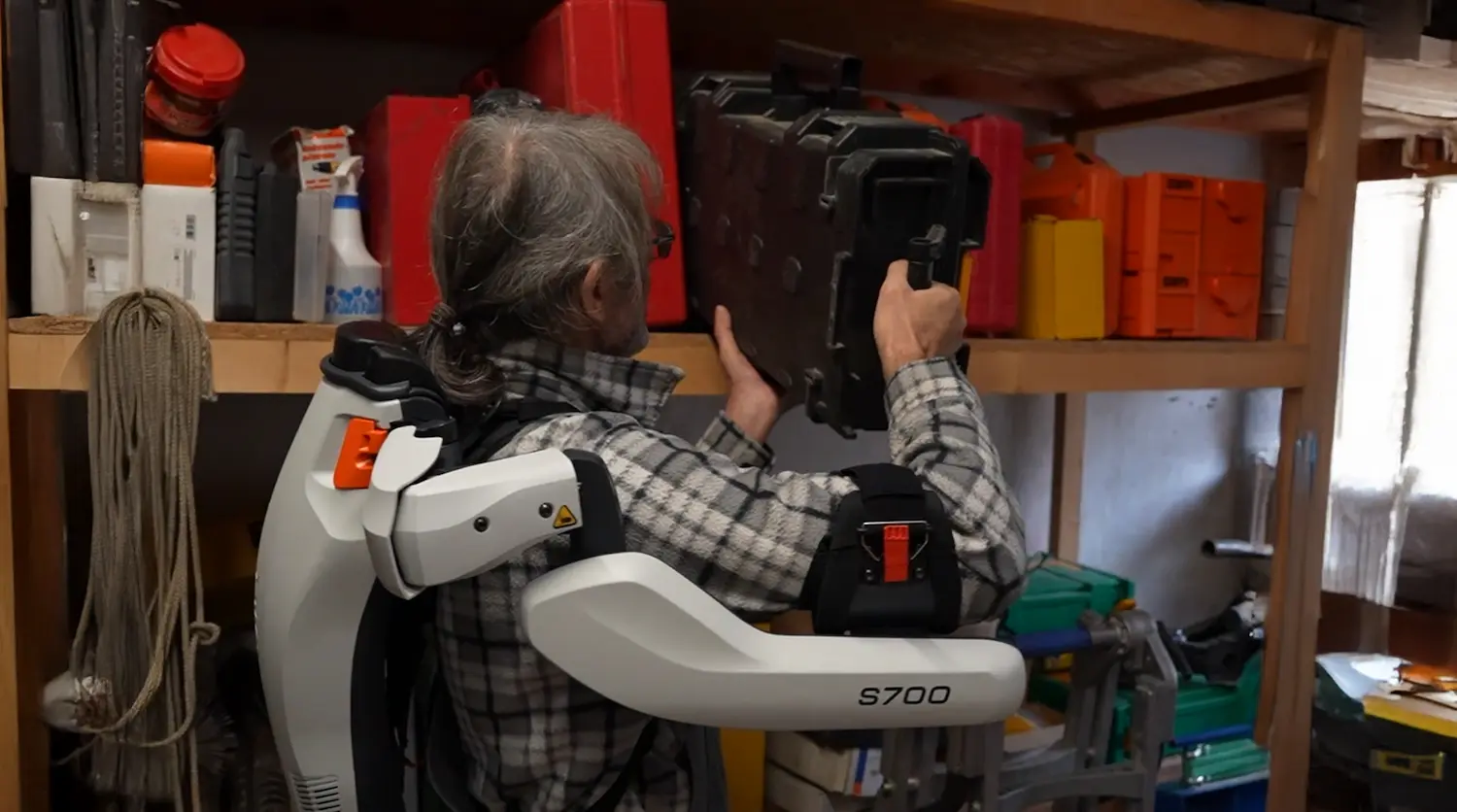 A man wearing an exoskeleton and holding a large case.
