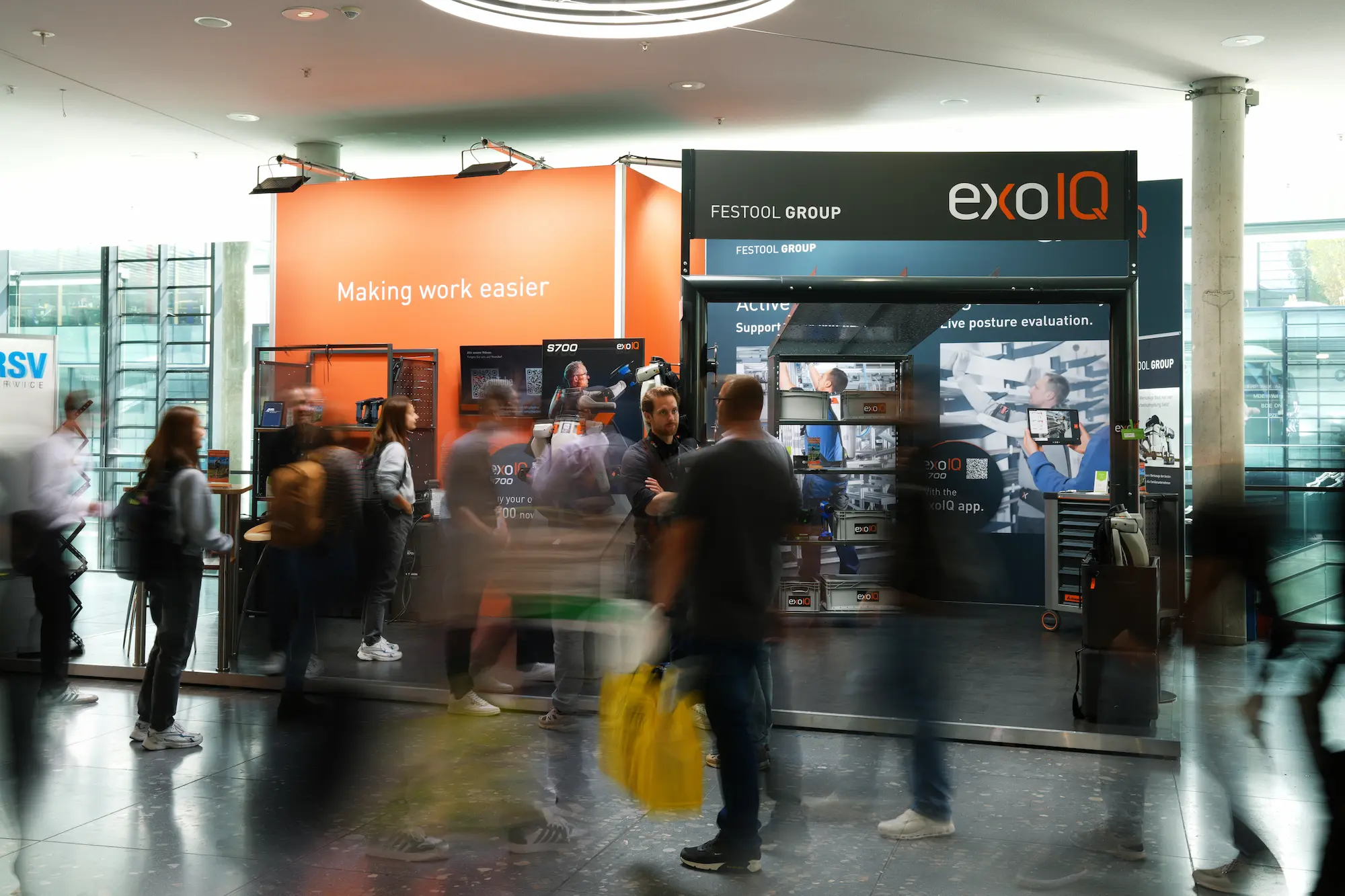 A group of people walking through an exhibition of exoIQ.