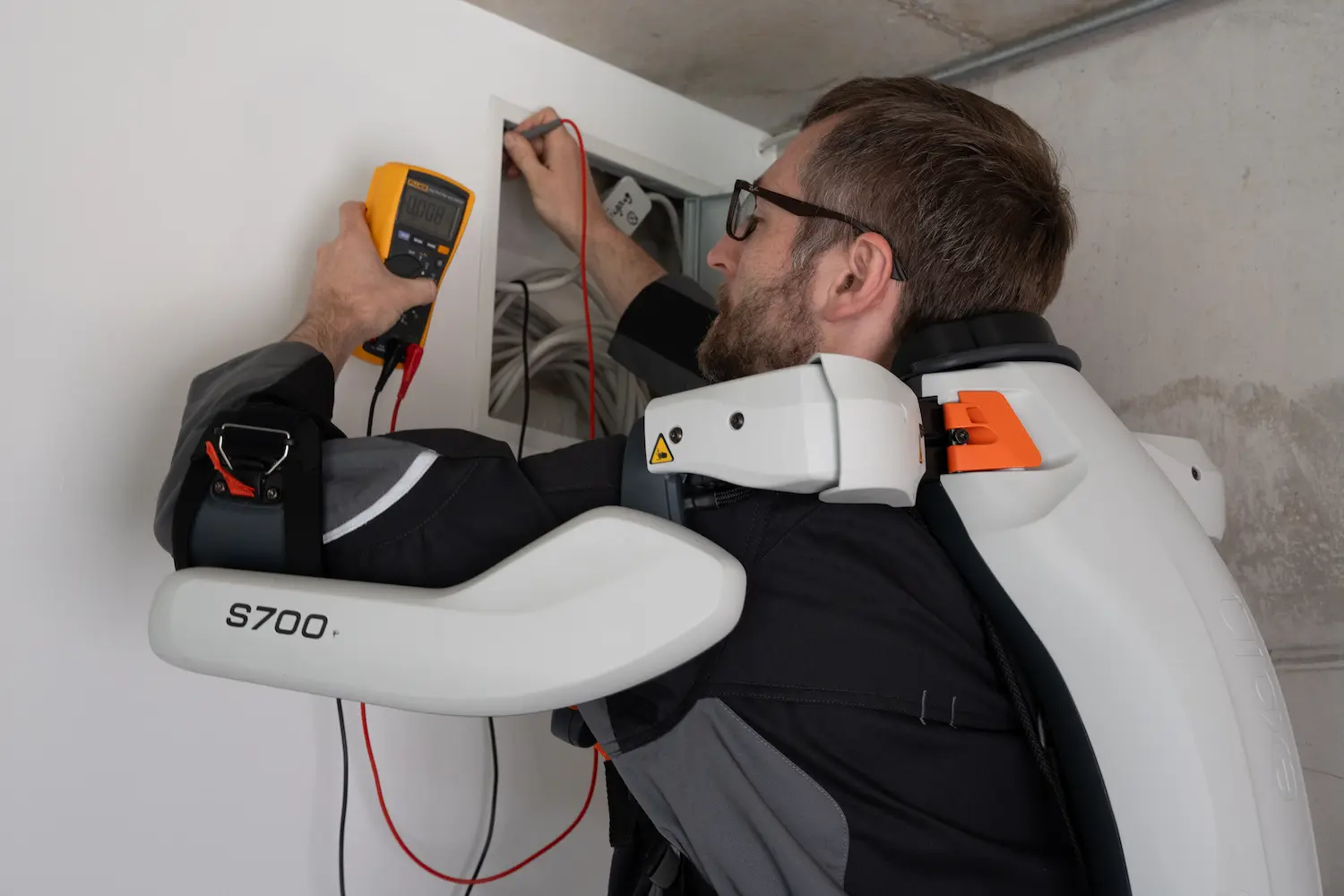 A man wearing an exoskeleton and glasses is working on electricity.