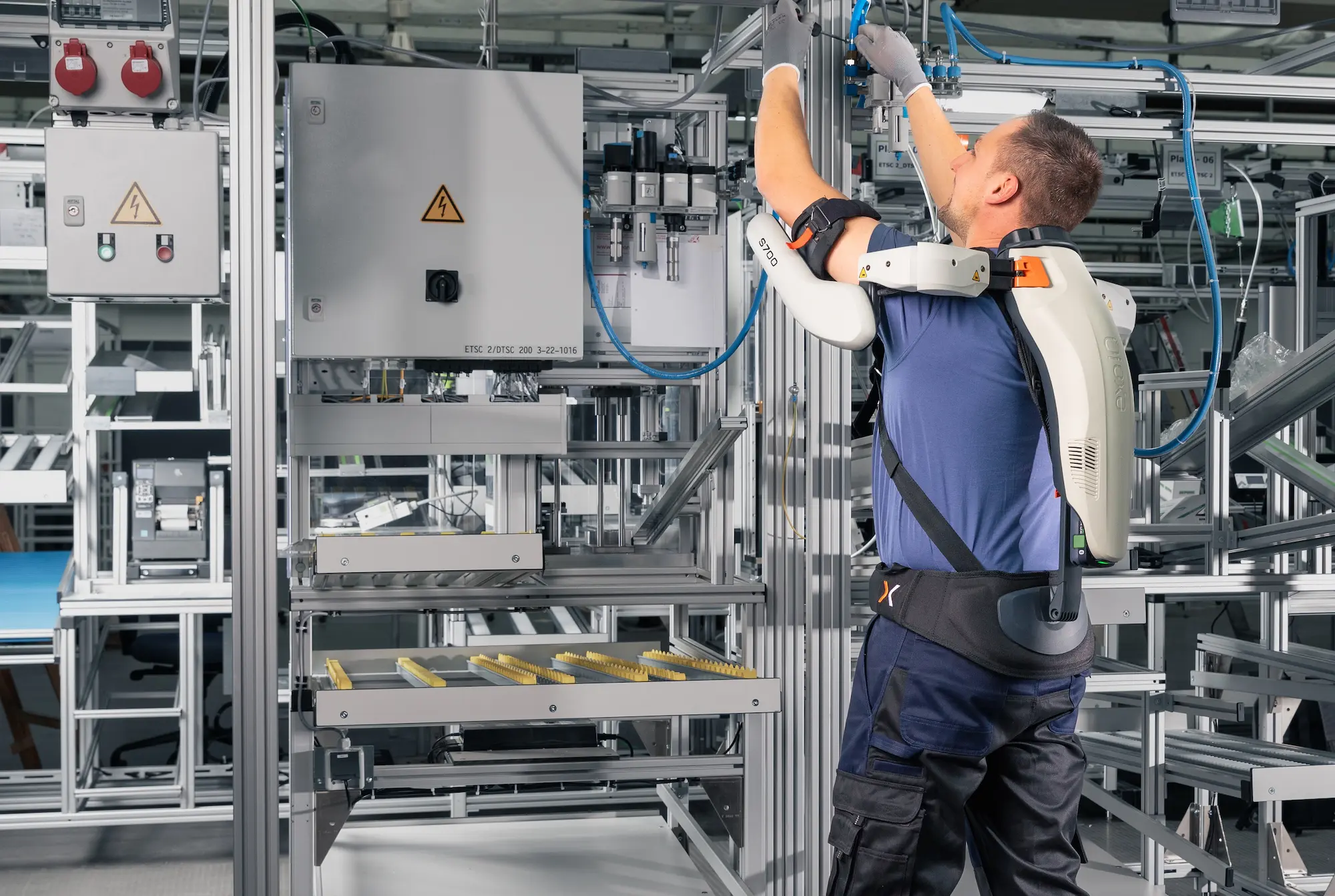 A man wearing an exoskeleton is working on a machine.