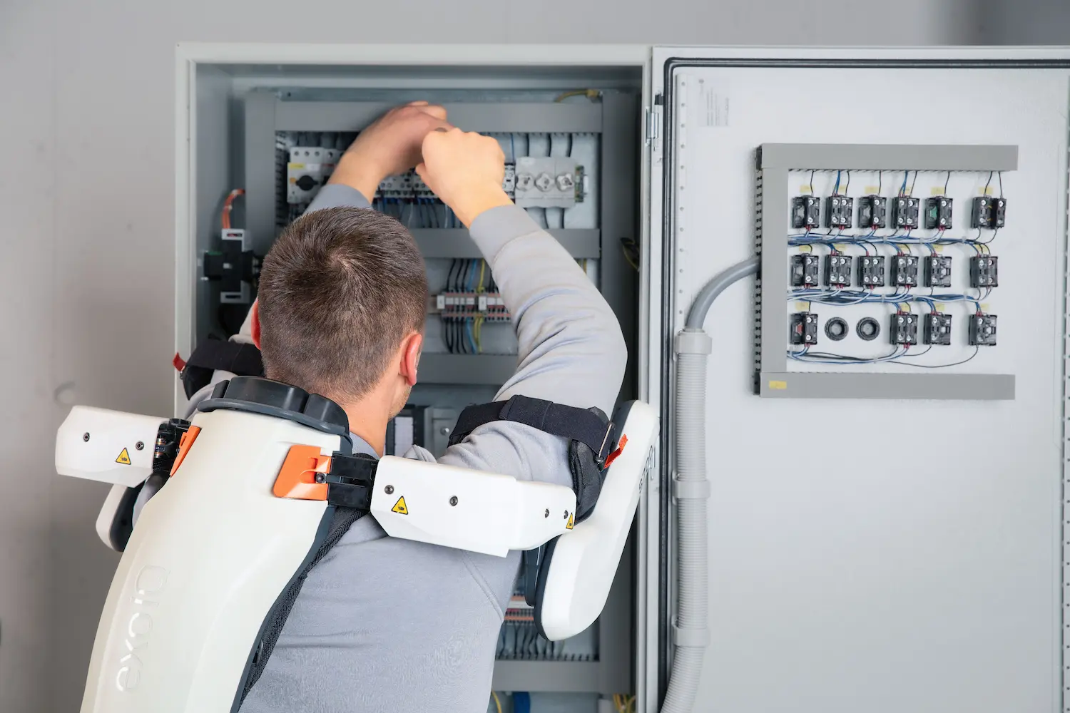 A man wearing an exoskeleton is working on an electricity installation.