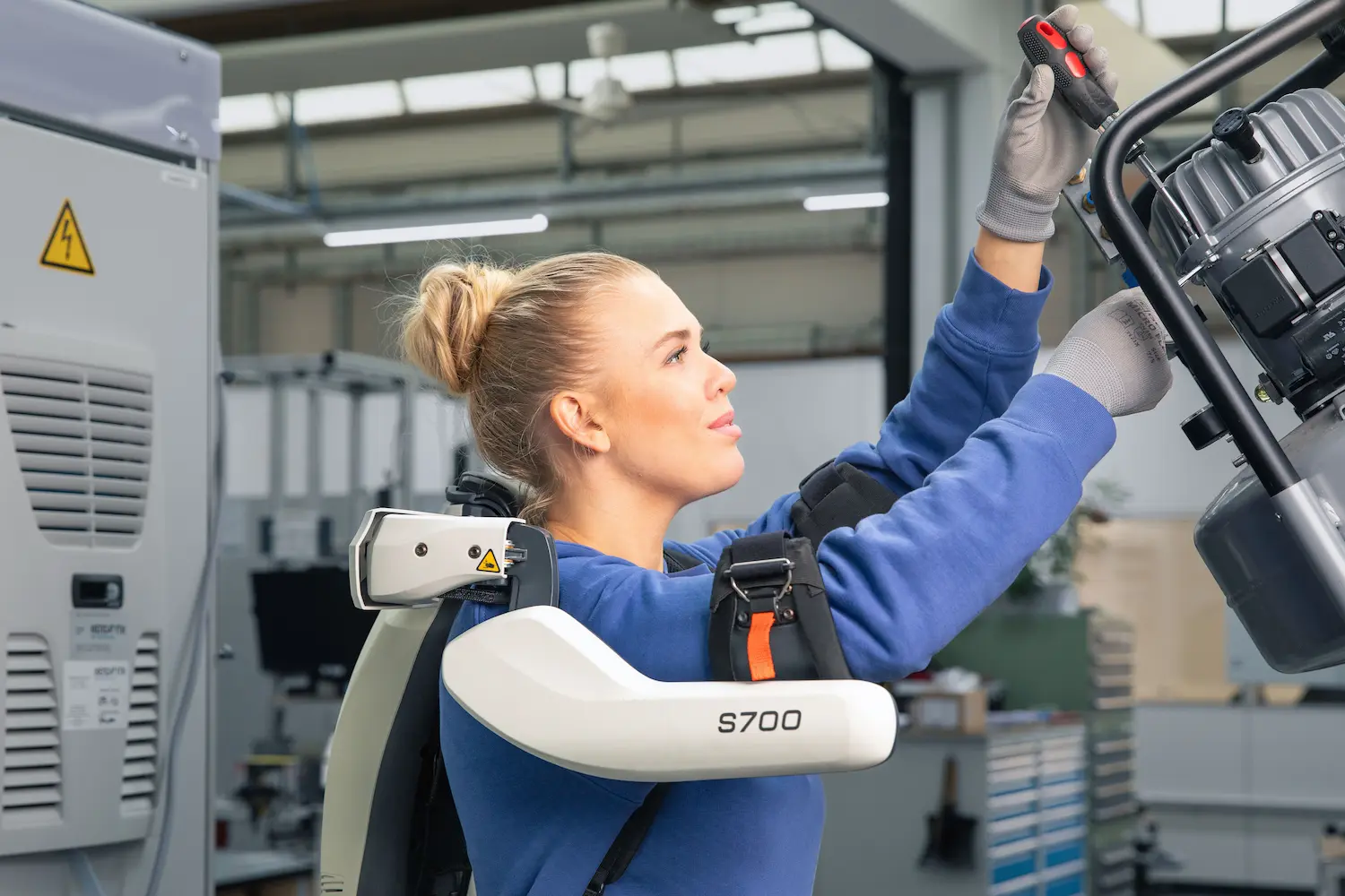 A woman wearing an exoskeleton working in production.