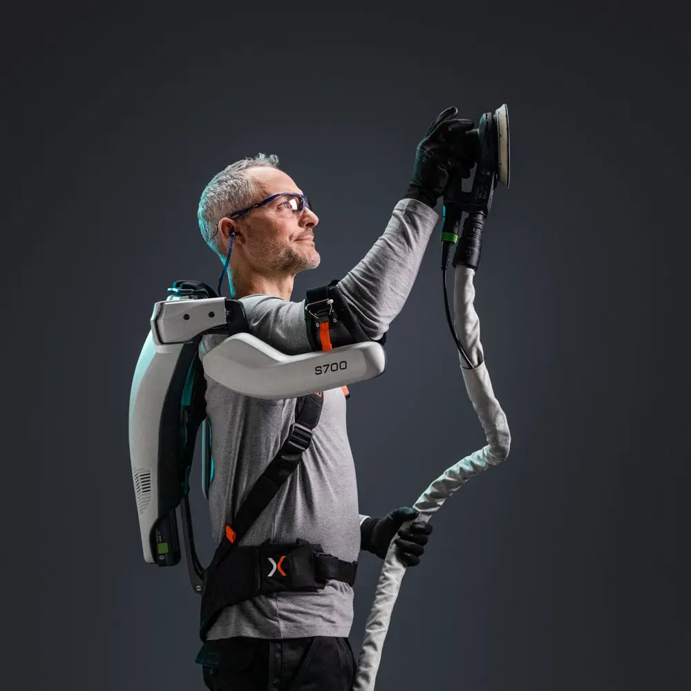 A man wearing a backpack and holding a large white object.