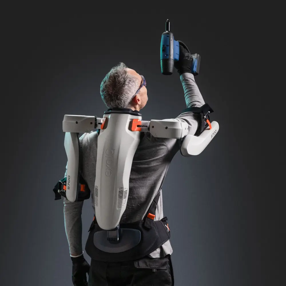 A man wearing an exoskeleton and holding a drill.