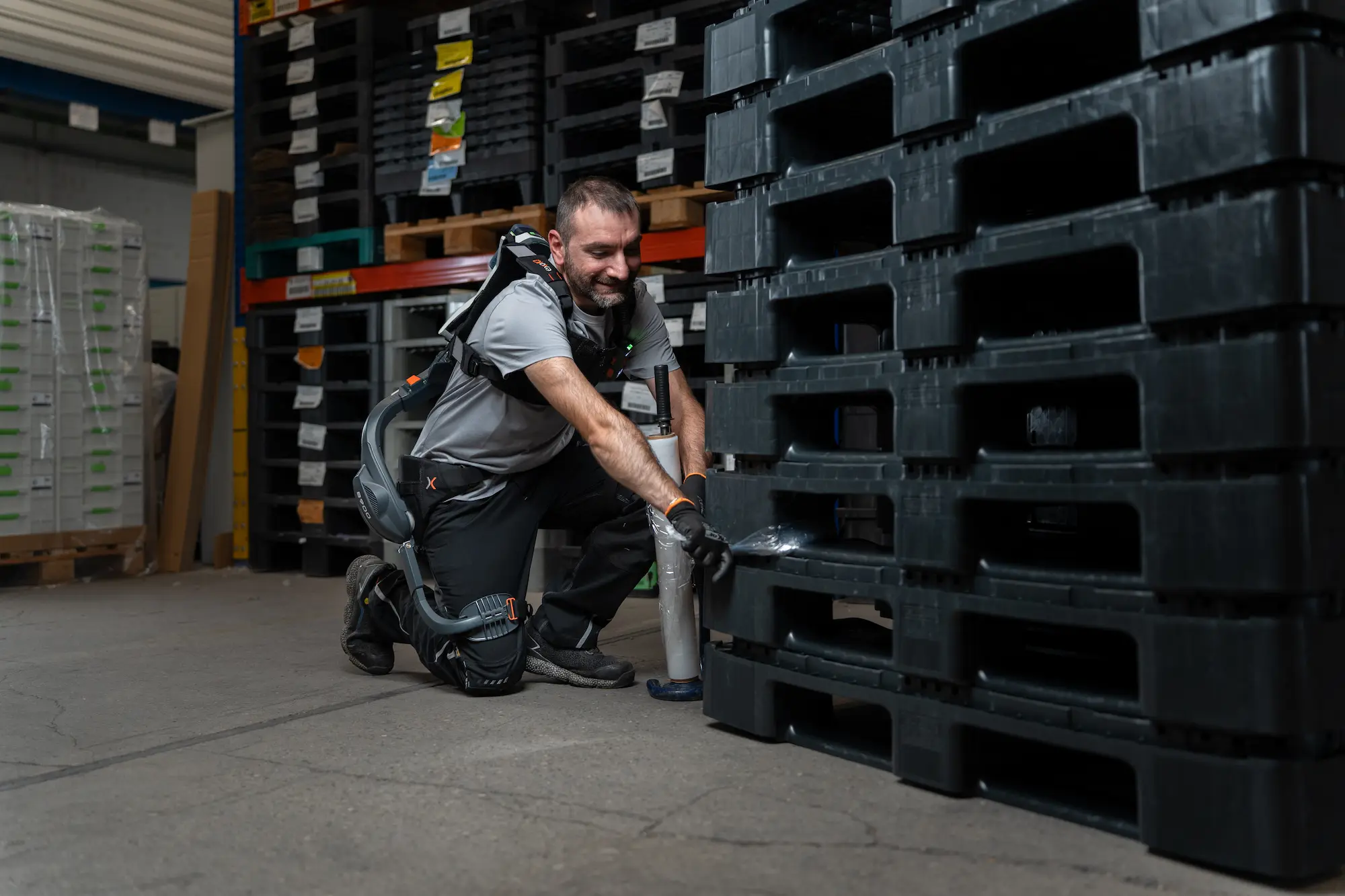 Mann mit einem aktiven Rücken-Exoskelett B900 arbeitet an einem Palettenstapel.