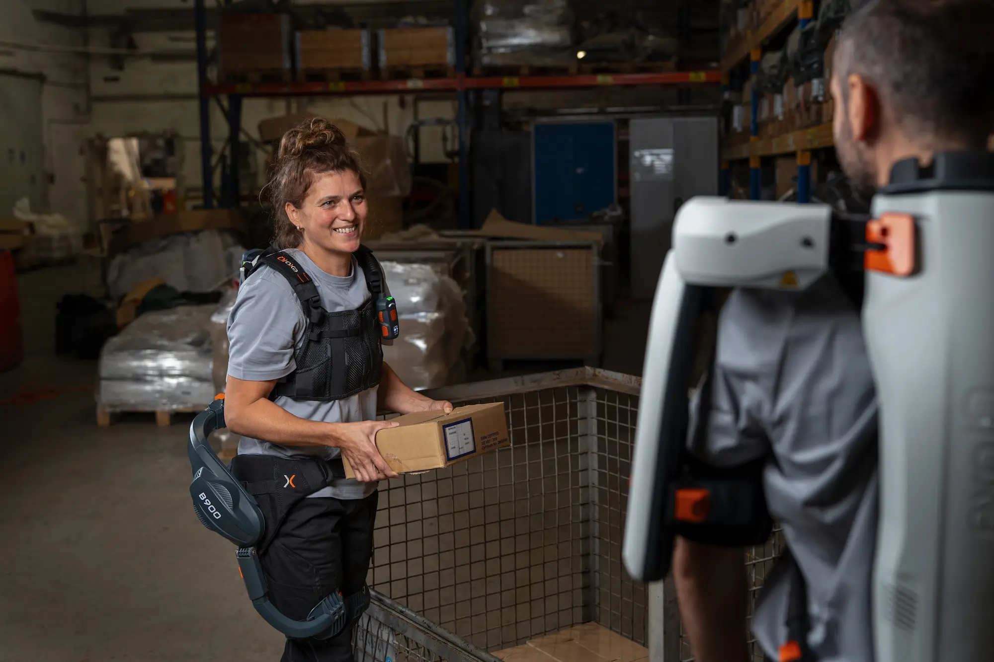 Frau mit einem aktiven Rücken-Exoskelett B900 hat einen Karton in der Hand.