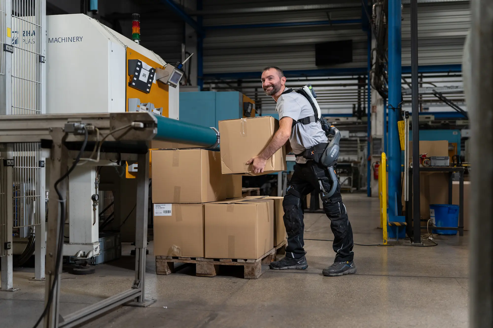 Mann mit einem aktiven Rücken-Exoskelett B900 arbeitet in einer Werkstatt.