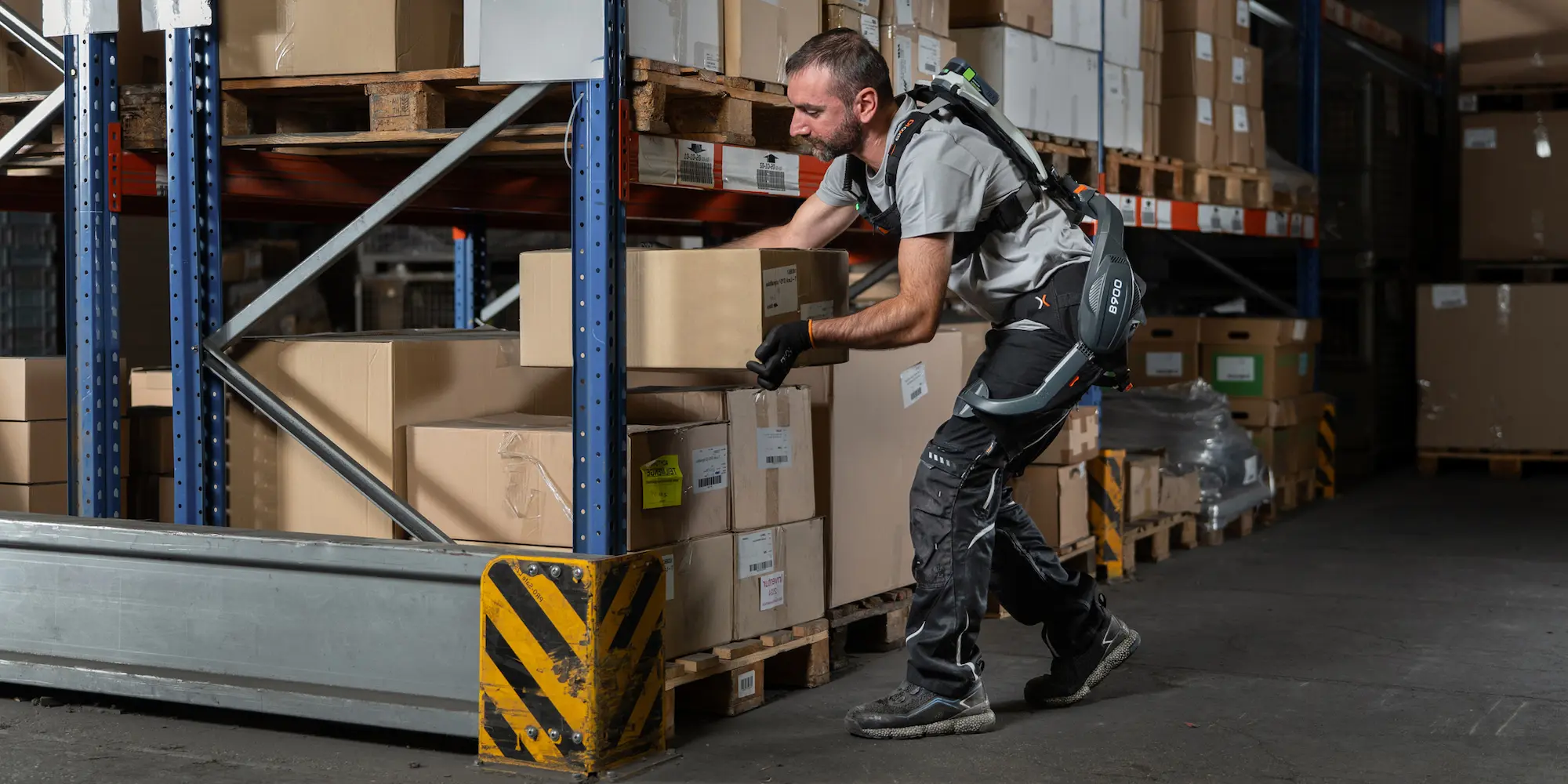 Mann mit einem aktiven Rücken-Exoskelett B900 arbeitet in einer Lagerhalle