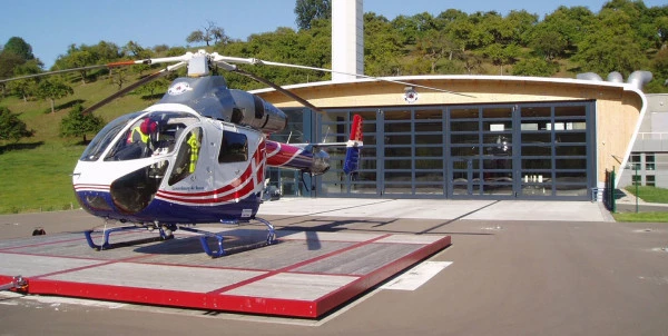 Hélicoptère Luxembourg Air Rescue sur une plateforme devant une base moderne de secours, illustrant les services médicaux d’urgence.