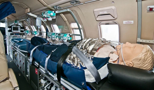 Intérieur d’un avion ambulance Luxembourg Air Rescue avec mannequin patient et équipements médicaux de réanimation avancée.