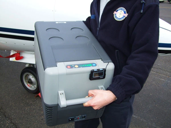 Personnel Luxembourg Air Rescue tenant un équipement médical portable pour missions d’ambulance aérienne et soins intensifs.