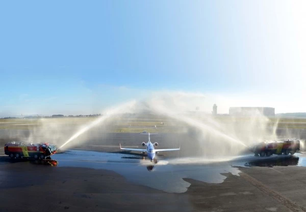 Jet ambulance Luxembourg Air Rescue accueilli par un salut d’eau sur piste, célébrant l’aviation et le transport médical.