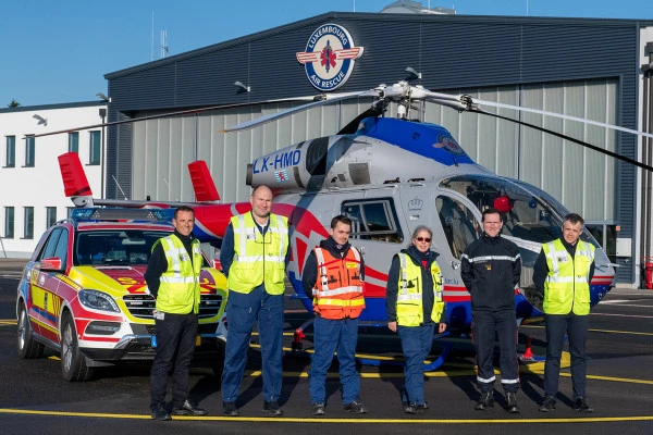 Équipe d’intervention Luxembourg Air Rescue devant un hélicoptère et un véhicule d’urgence devant la base opérationnelle.