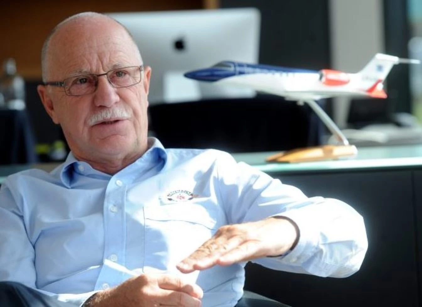 René Closter, founder of Luxembourg Air Rescue, speaking during an interview in an office with a model air ambulance aircraft in the background.