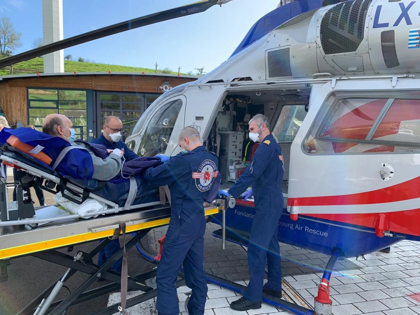 Medizinisches Team von Luxembourg Air Rescue bringt einen Patienten auf einer Trage in einen Rettungshubschrauber während eines Einsatzes.