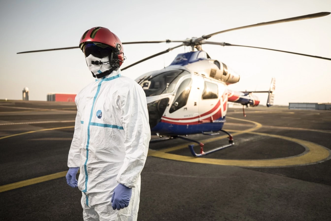 Luxembourg Air Rescue rescuer in protective gear standing in front of a rescue helicopter on the helipad at Findel.
