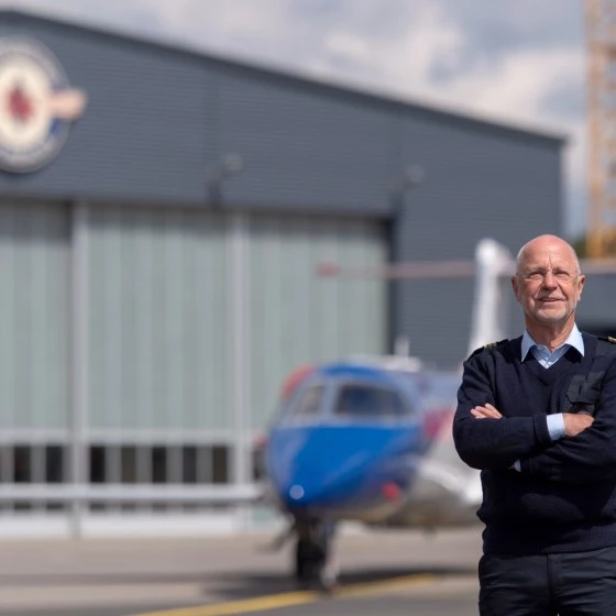 René Closter, founder of Luxembourg Air Rescue, standing in front of an air ambulance aircraft on the tarmac at Findel.
