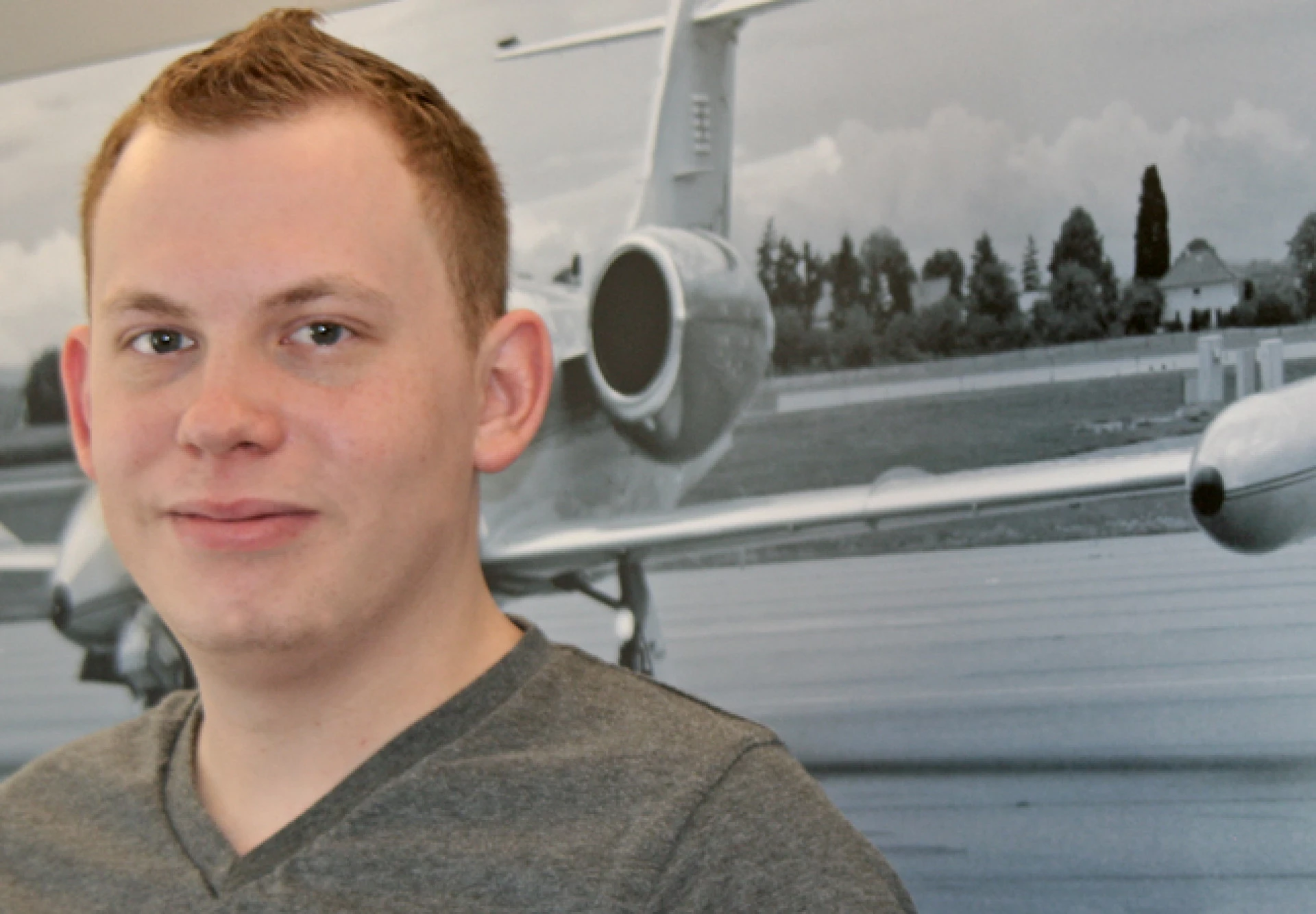 Portrait d’un jeune homme en intérieur avec une image d’avion en arrière-plan