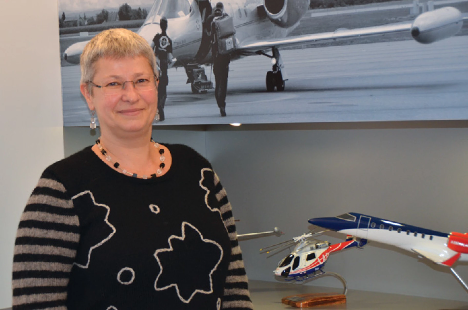 Femme debout en intérieur près de maquettes d’aéronefs et d’images d’aviation