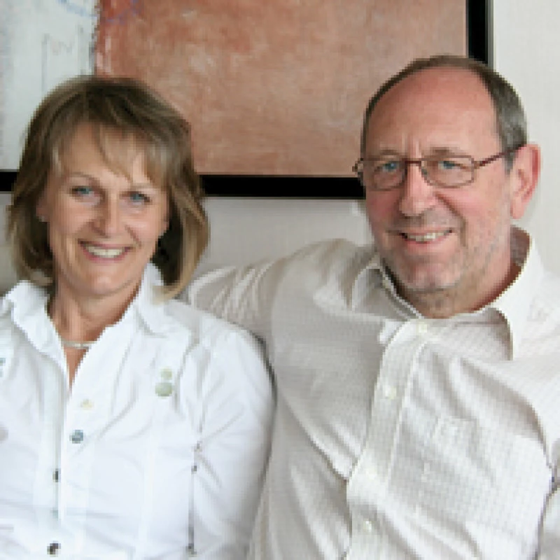 Lächelndes Paar sitzt auf einem Sofa mit Kunstwerk im Hintergrund