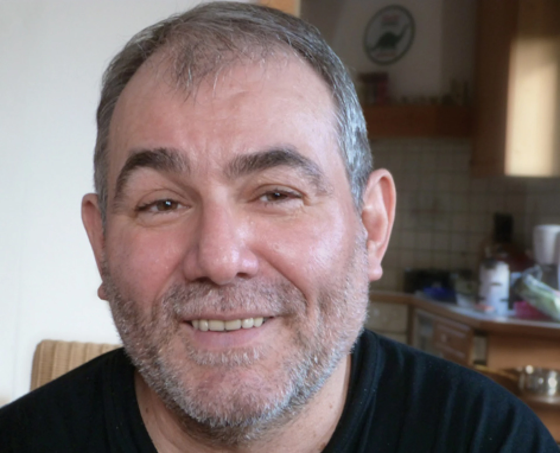 Close-up portrait of a smiling middle-aged man indoors.