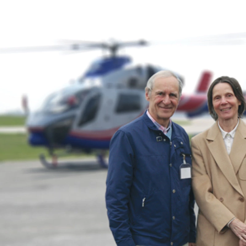 Erwachsenes Paar steht im Freien mit einem Hubschrauber im Hintergrund