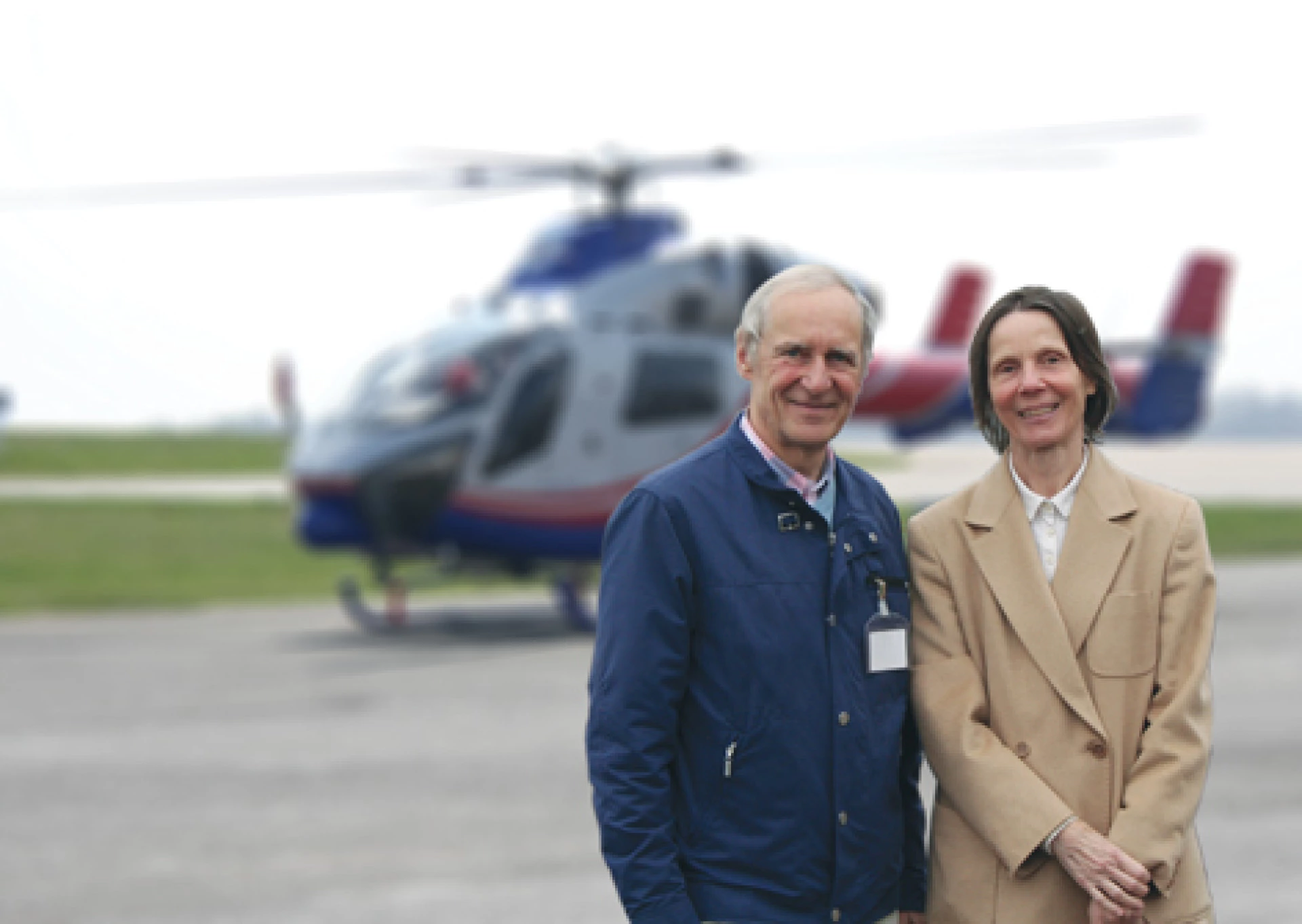 Erwachsenes Paar steht im Freien mit einem Hubschrauber im Hintergrund