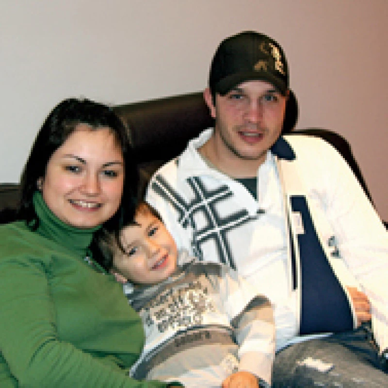 Family sitting together on a sofa with a young child indoors