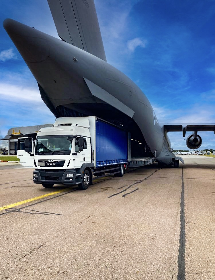 MAC Courier Services truck reversed up to the ramp of a large transport plane.