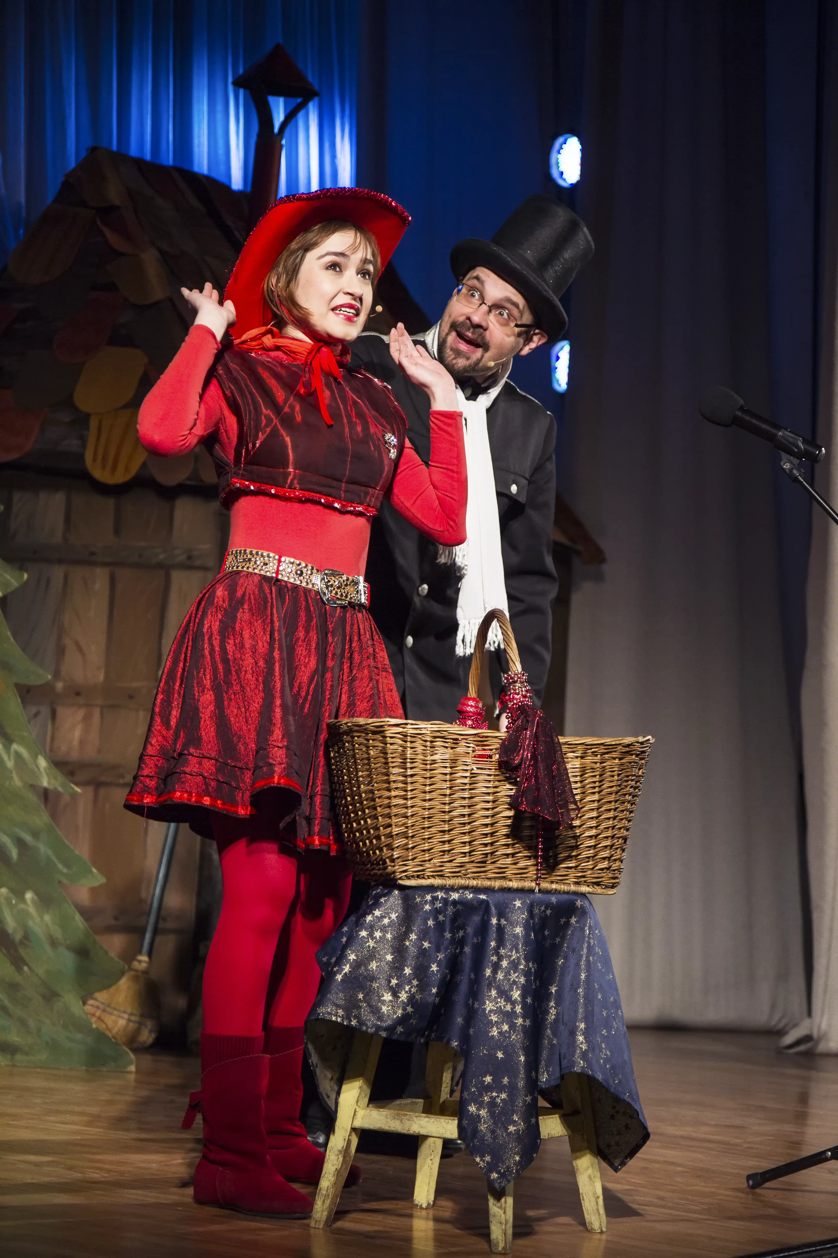 Spektakl dla dzieci – Czerwony Kapturek – Aktorka w czerwonym kapturze i koszykiem na scenie.