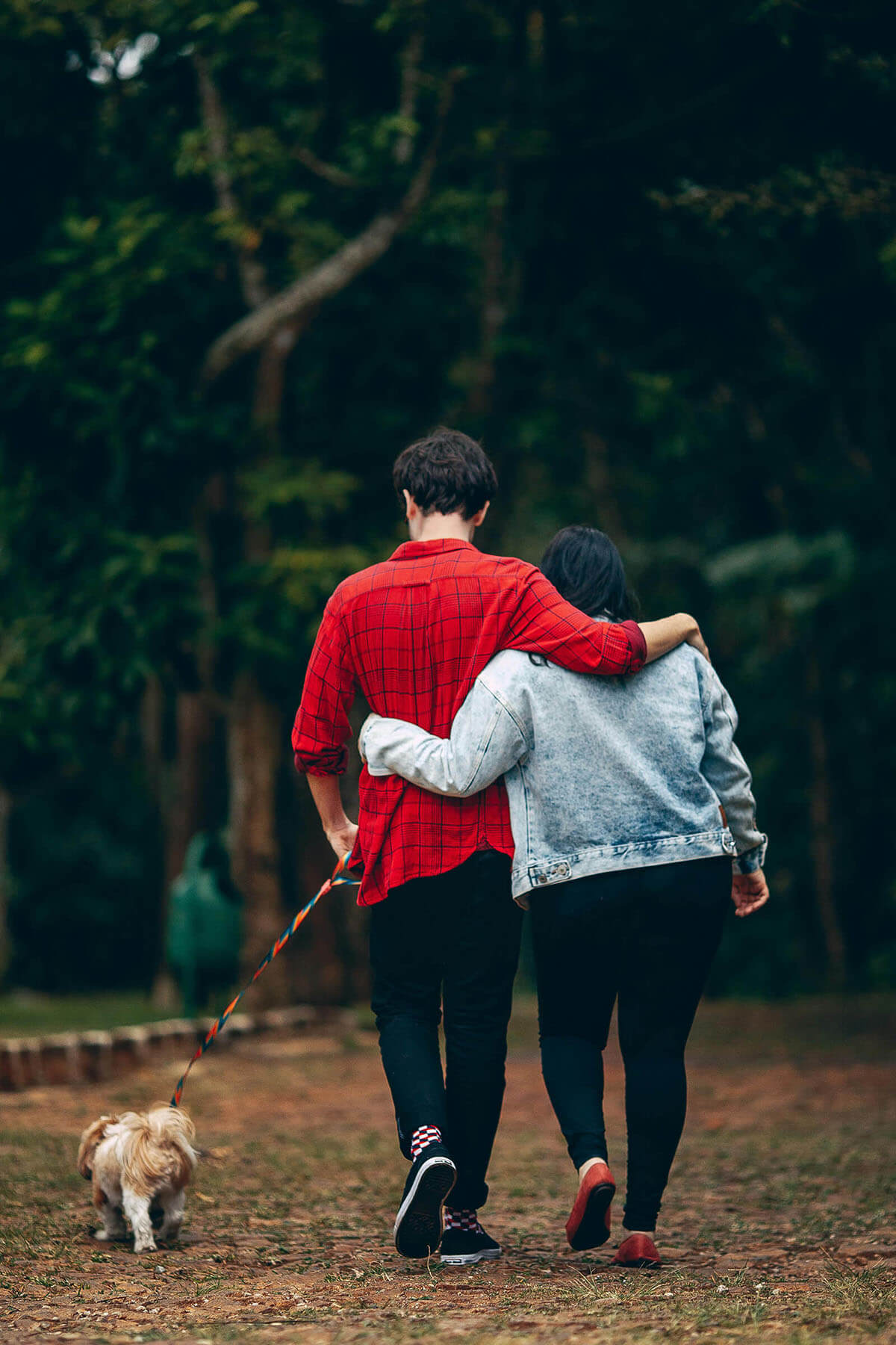 couple walking in woods with dog
